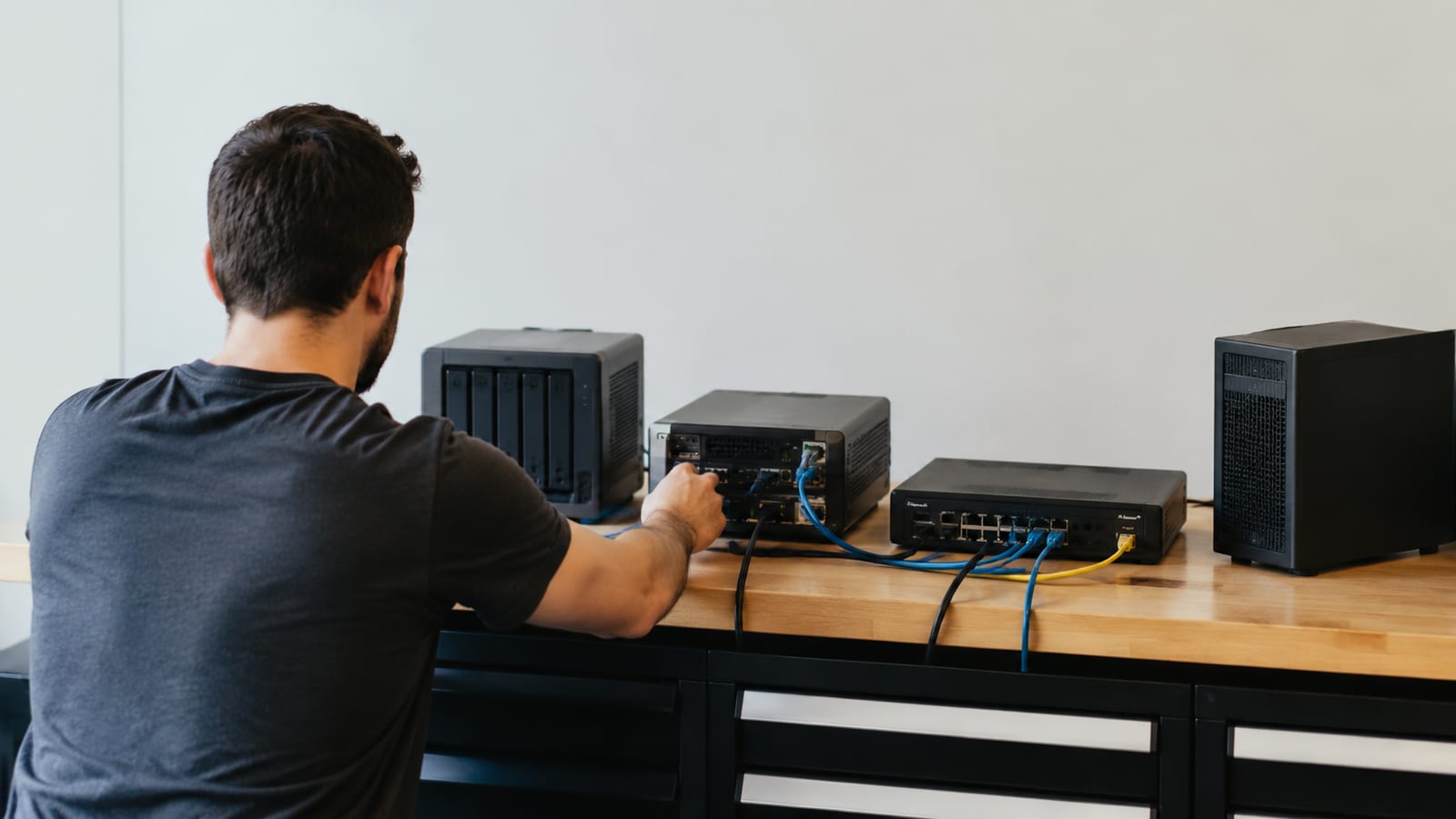 Home lab administrator checking compact servers, router hardware, and network cables during troubleshooting