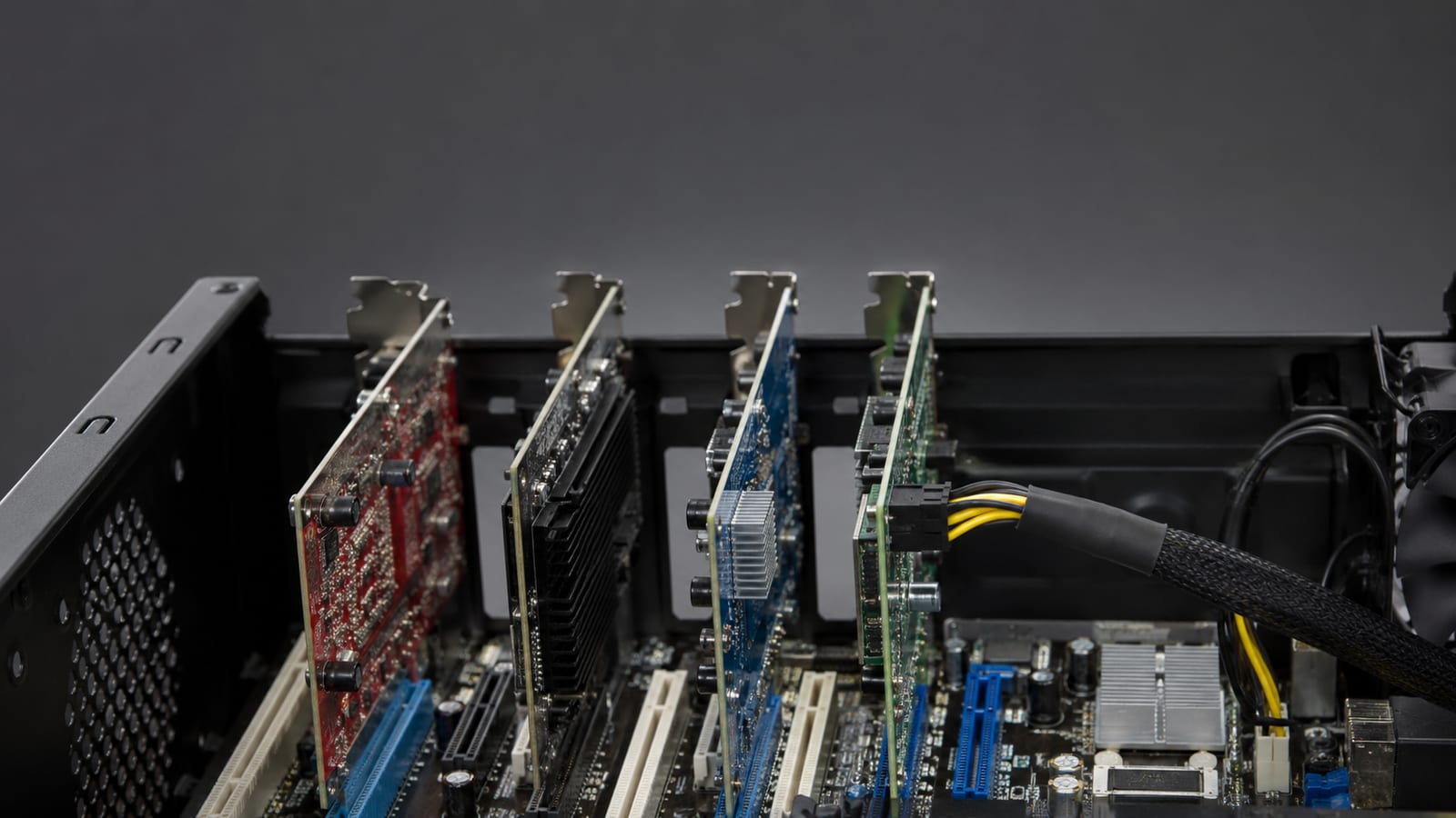Close-up of PCIe expansion cards seated in a server motherboard beside data cables, no labels